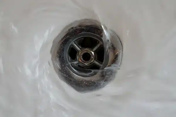 Water swirling down a metal drain in a sink with a visible vortex pattern, much like the efficient work of a rooter service clearing away clogs.