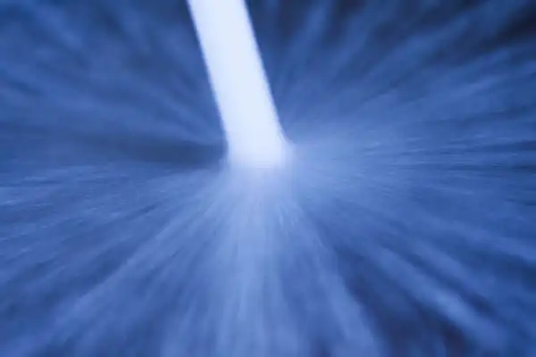 Abstract image of blue radial light beams converging toward a bright center point, resembling the dynamic force of hydro jetting.