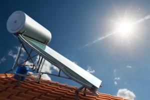 Solar water heater on a roof under a clear sky with bright sunlight.